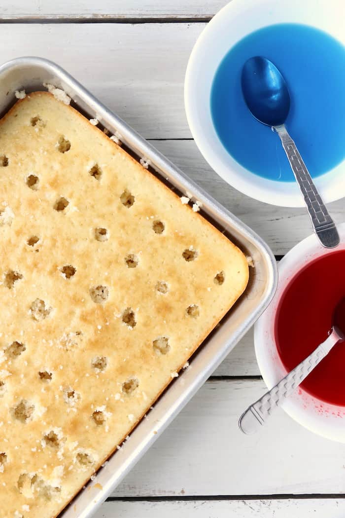 Show your American pride with this Patriotic Jello Poke Cake! Moist, delicious cake drizzled with sweet, colorful jello, all covered with whipped topping! #InspirationalMomma #jellopokecake #pokecake #America #4thofJuly #jello #cake #dessert #desserts #recipe #patriotic #redwhiteblue