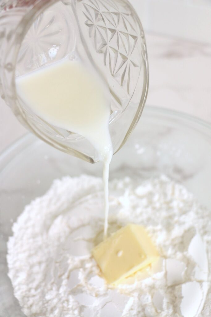 Milk being poured into bowl with butter and powdered sugar