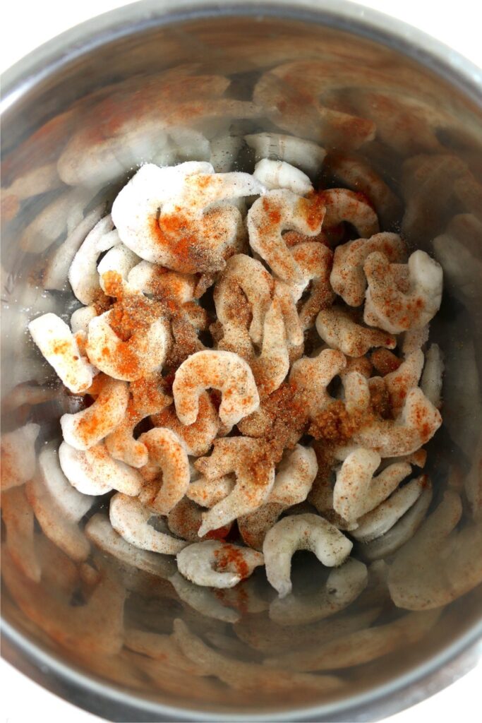 Overhead shot of bowlful of frozen shrimp topped with seasoning