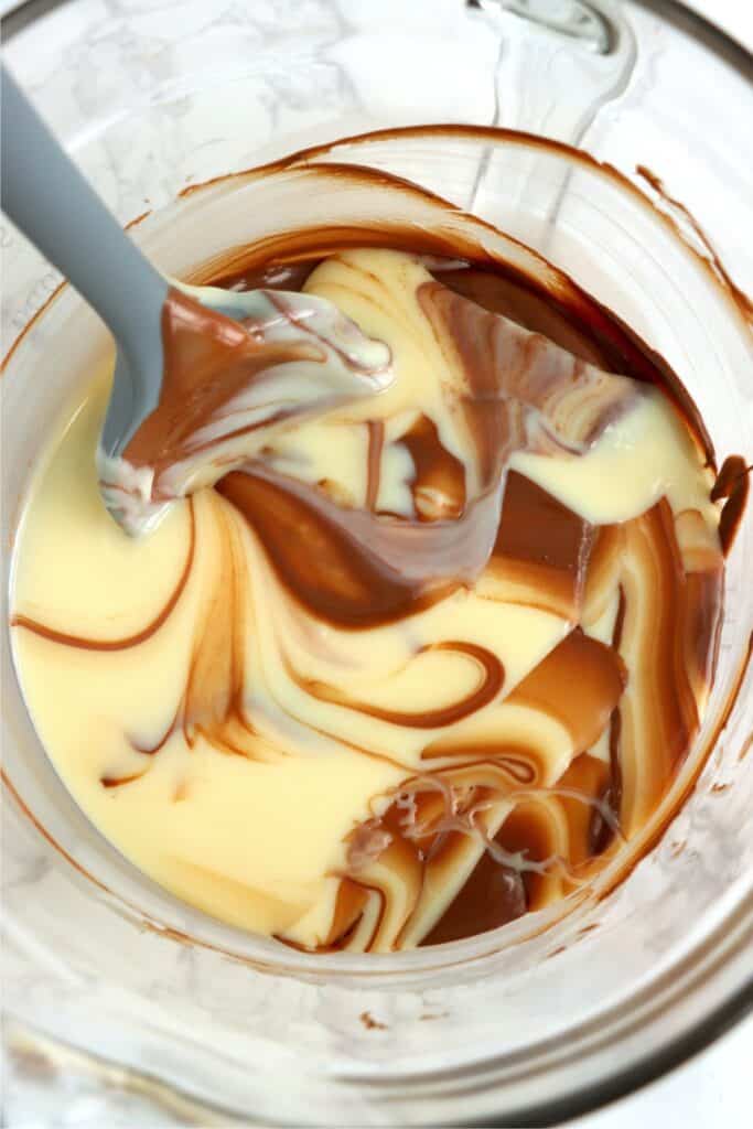 Overhead shot of spatula mixing chocolate and sweetened condensed milk in a mixing bowl