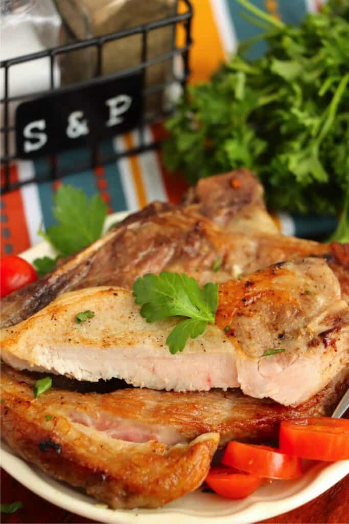 Closeup shot of two reverse sear pork chops stacked atop one another with the top chop cut in half.