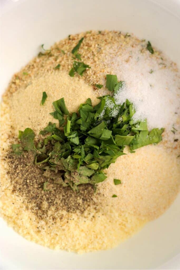 Overhead shot of bowlful of seasonings, breadcrumbs, parmesan cheese, and oil. 