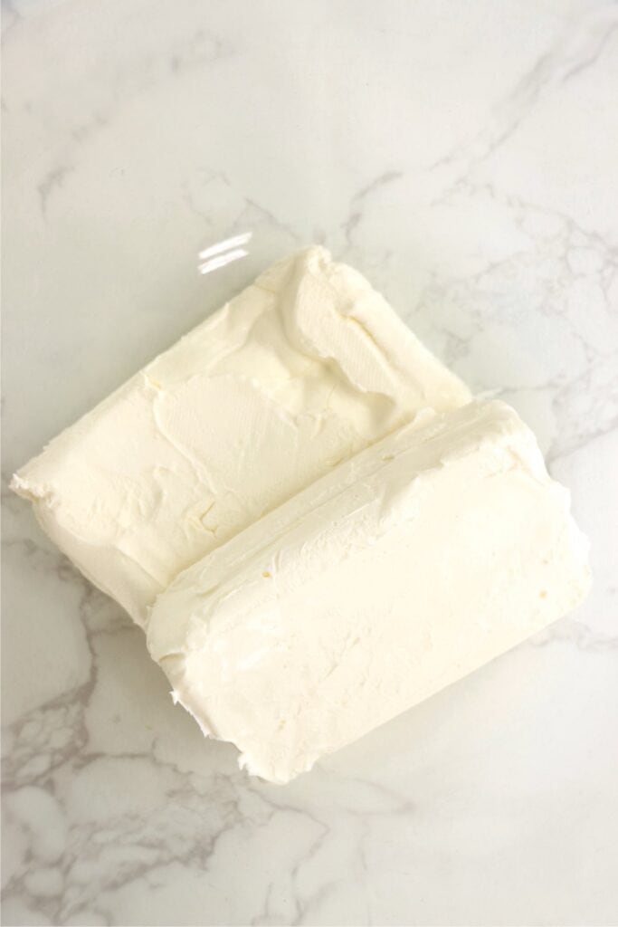 Overhead shot of two blocks of cream cheese in mixing bowl. 