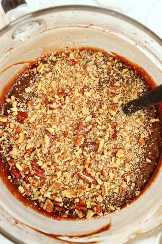 Overhead shot of pecans being mixed into brownie batter. 