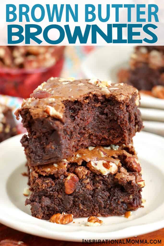 Two brown butter brownies stacked atop one another with bite taken out of top brownie. 